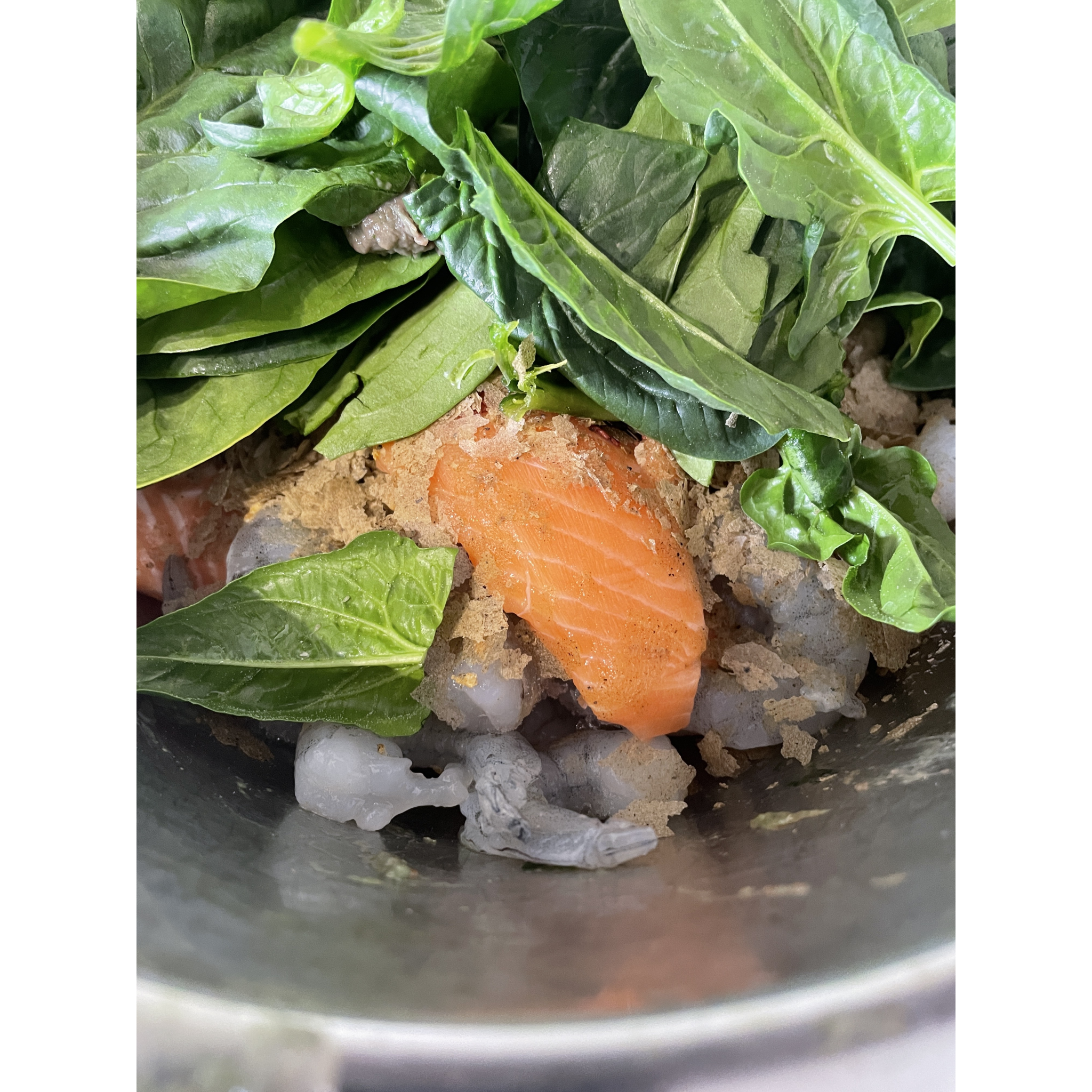 Image shows what goes into SimplyFish homemade beefheart mix showing salmon, spinach, garlic, shrimp and other ingredients in a metal bowl